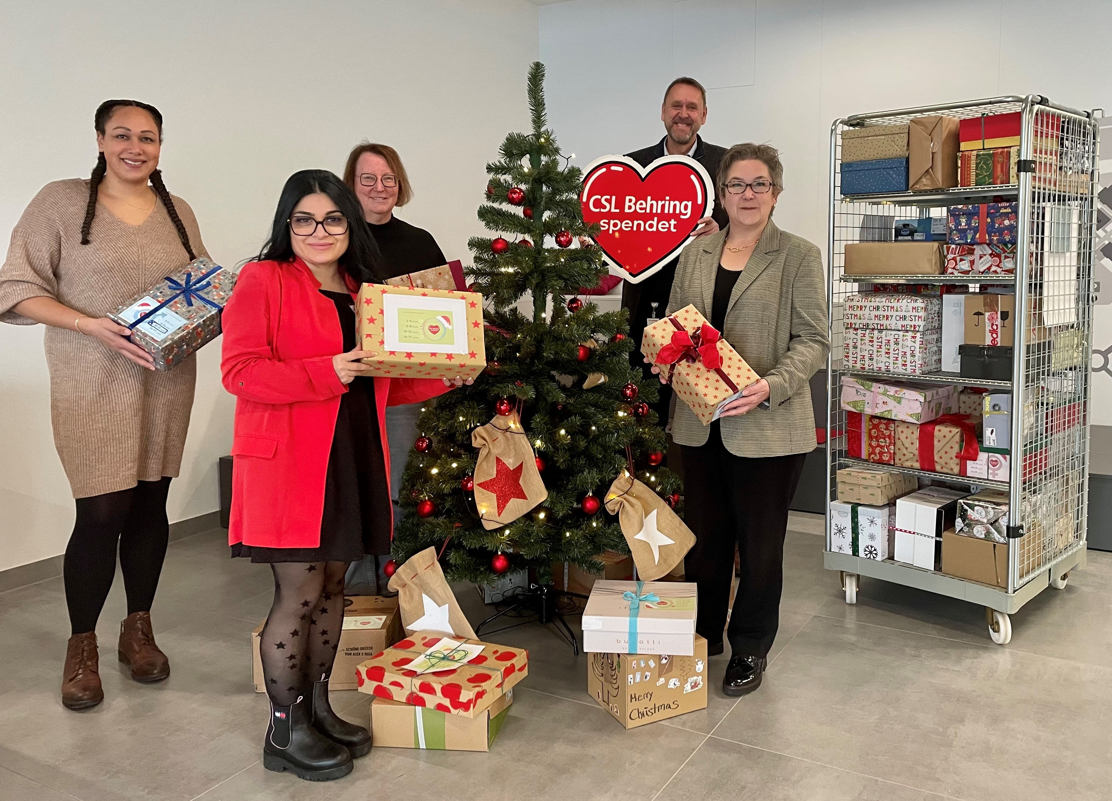 Group of people in front of a Christmas Tree with gifts