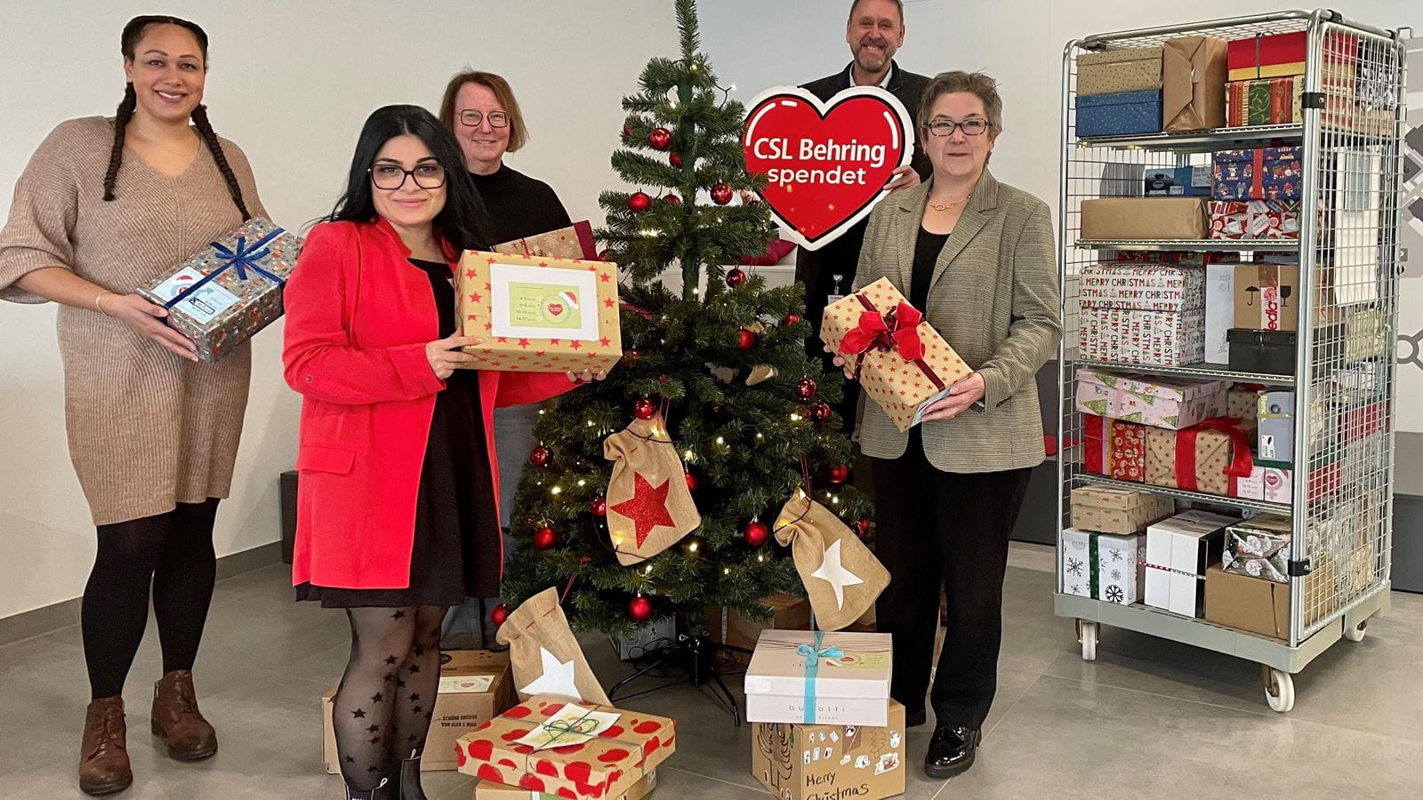 Group of people in front of a Christmas Tree with gifts