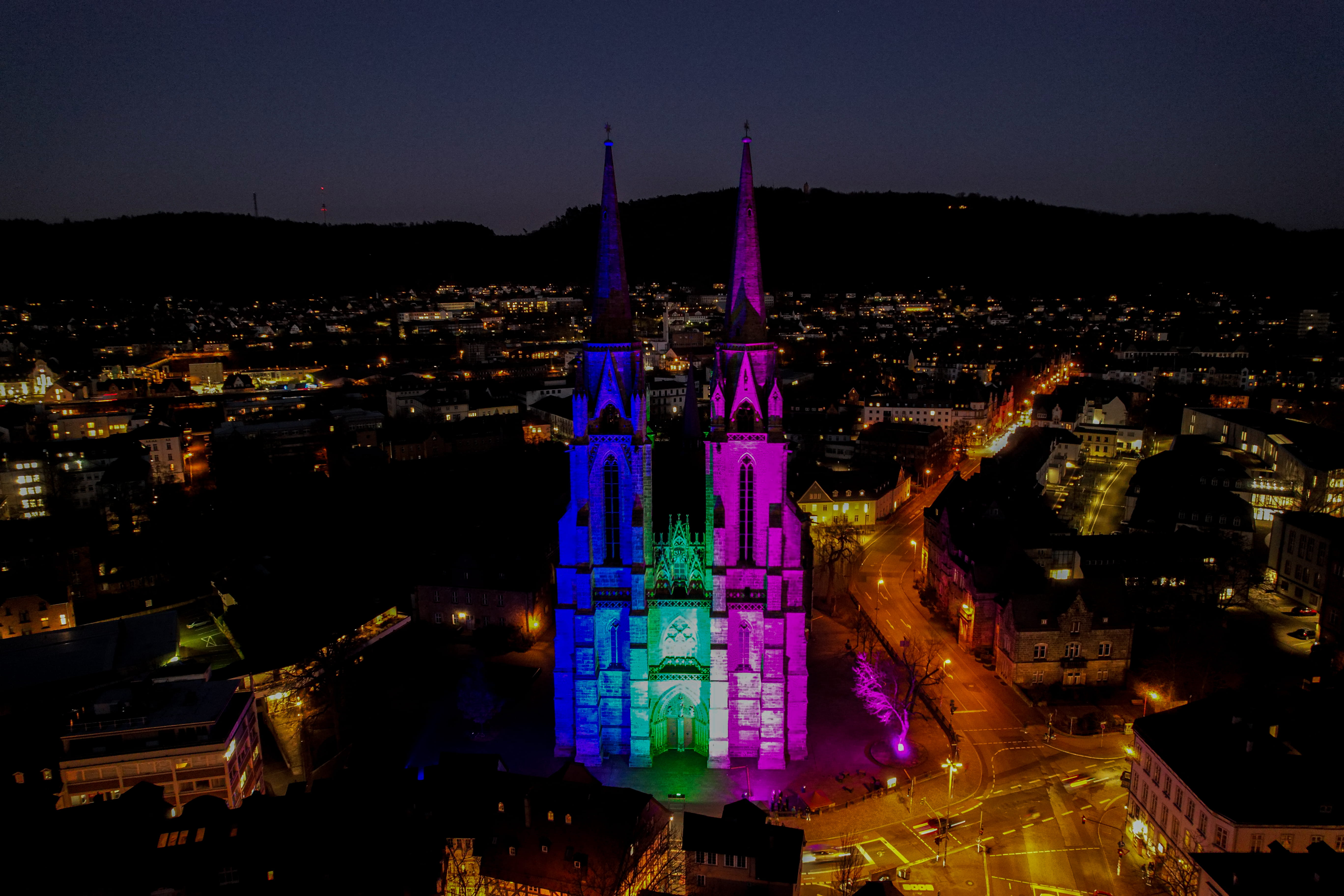 Drohnenaufnahme der angestrahlten Elisabethkirche in Marburg